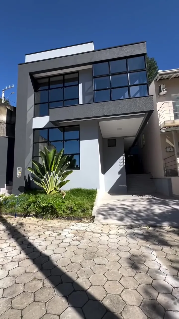 Fachada de residência contemporânea em Balneário Camboriú, com esquadrias escuras e vidro