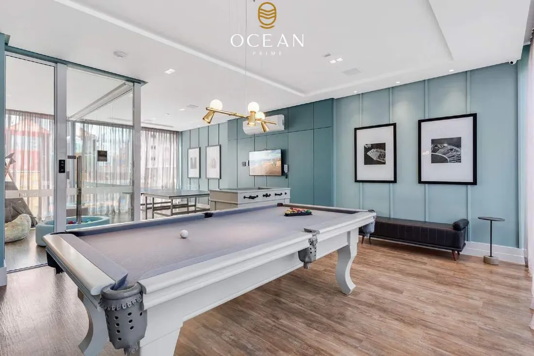 Sala de estar com mesa de sinuca, painel azul claro e piso de madeira
